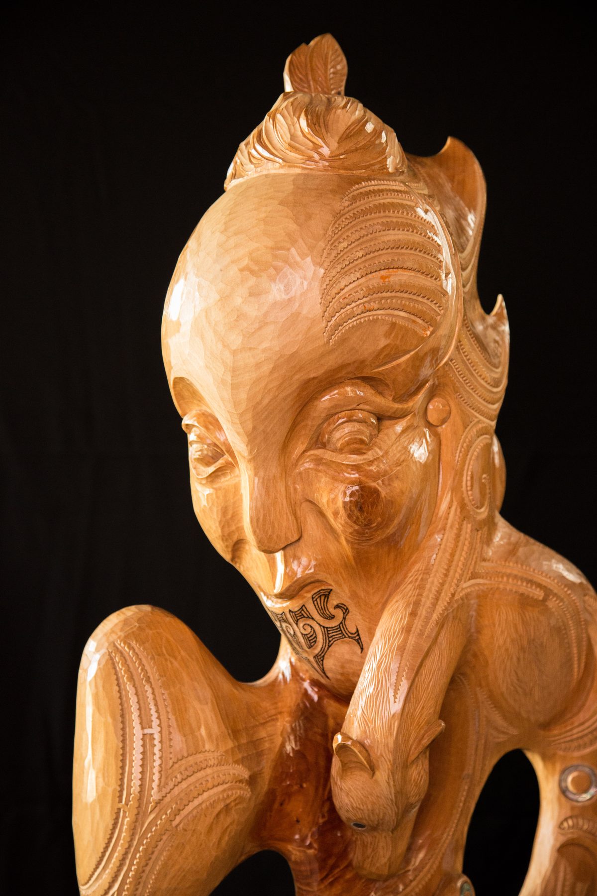 Niwareka: the face, eyes lowered, a hand raised to the mouth, moko on the chin.