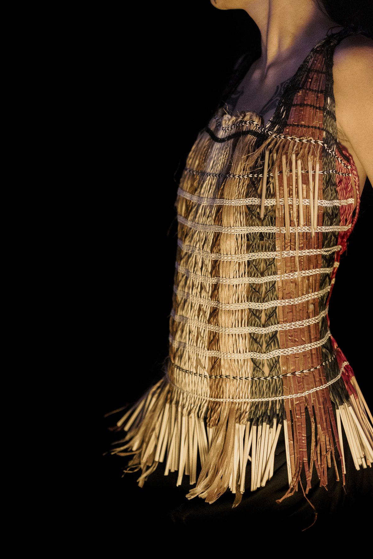 Raranga by Ruth Woodbury: a woven bodice with a fringed hem, worn, seen from the side.