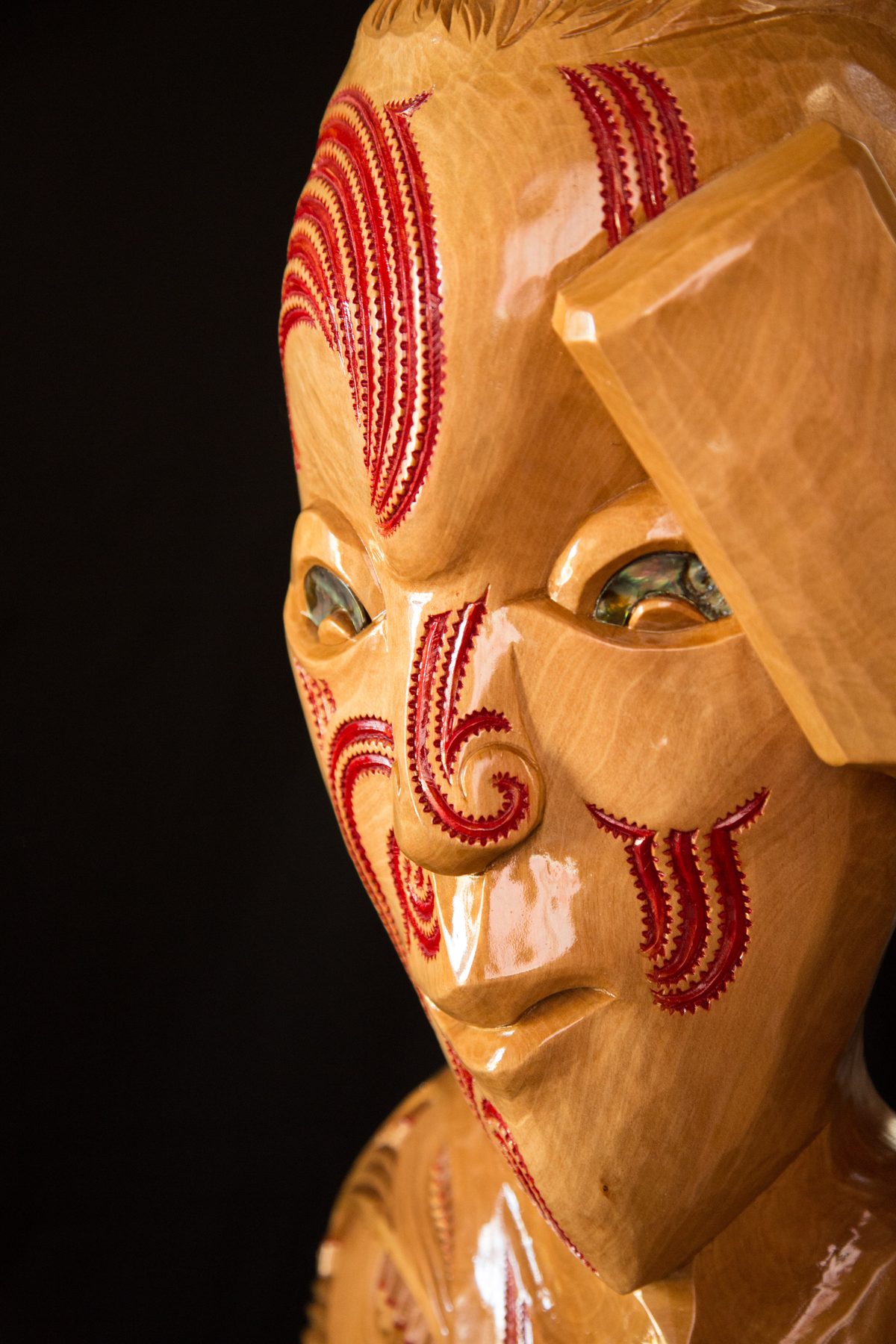 Rua: the face, red moko and pāua eyes.